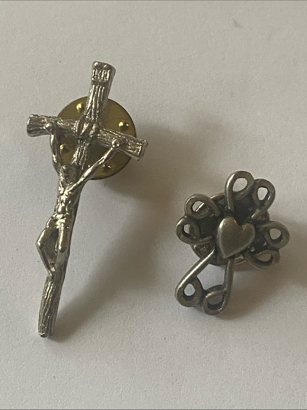Two religious tax pins, one crucifix and one fancy cross with a heart